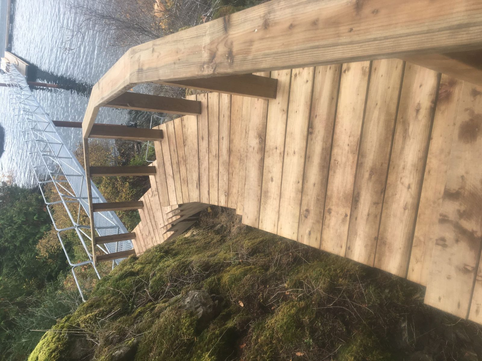 Freshly built cedar stairs and deck on a mossy rock outcrop overlooking the water