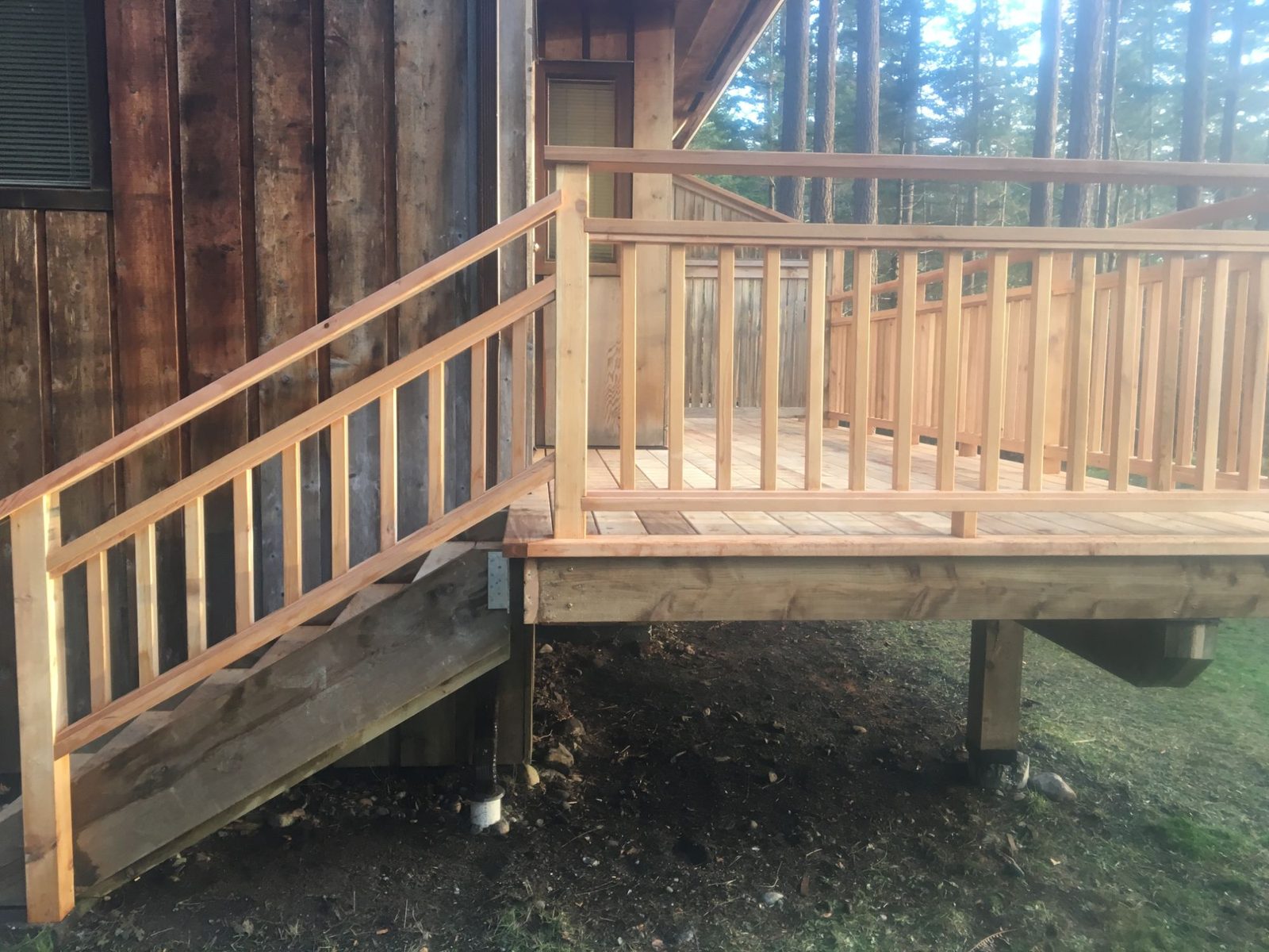 Cedar deck with built-in bench, matching railing and side staircase beside a wood-sided cabin
