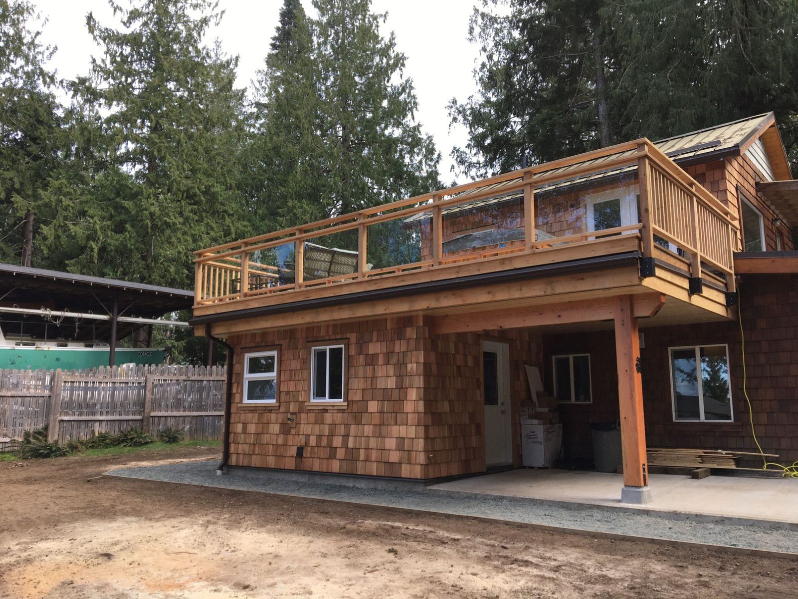 Elevated cedar-shingled building with rooftop hot tub deck and glass railing on Quadra Island