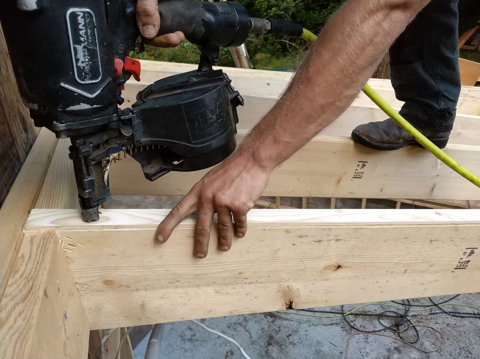 Carpenter using a nailer on dimensional lumber framing on Quadra Island