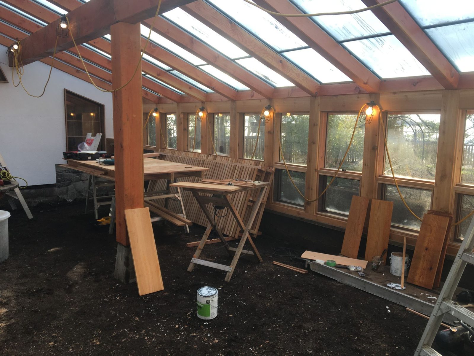 Interior of a timber frame sunroom under construction with glass roof, large windows and exposed posts
