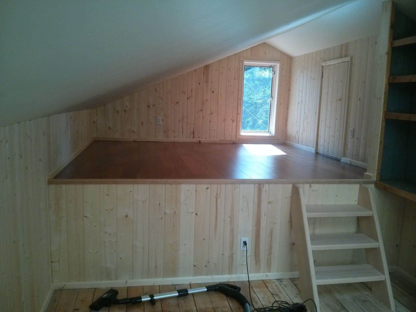 Tiny home loft interior with pine board walls, hardwood floor and a custom built wood ladder on Quadra Island