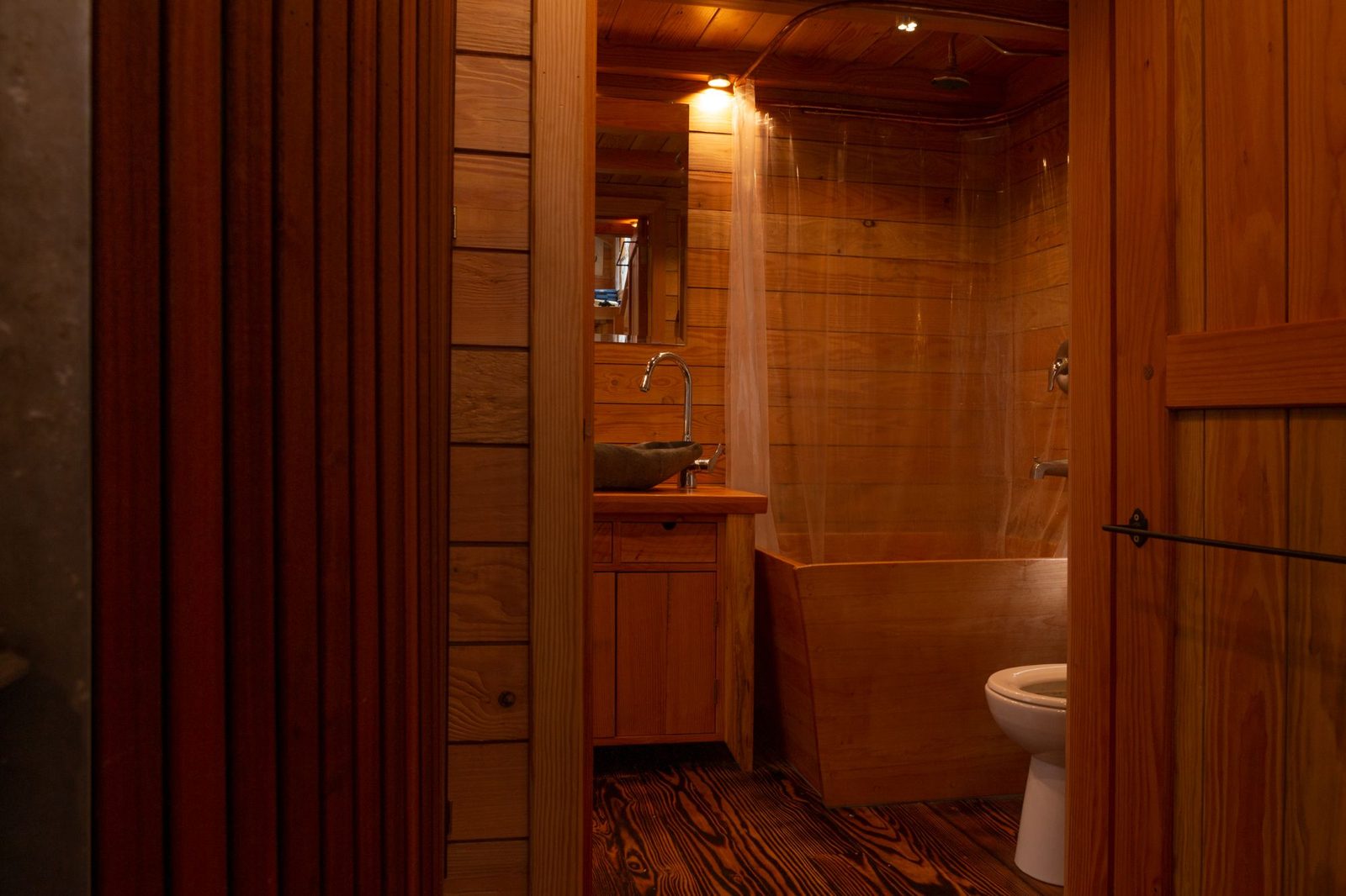 Wood-clad tiny home bathroom with vessel sink, soaking tub, shower and toilet on Quadra Island