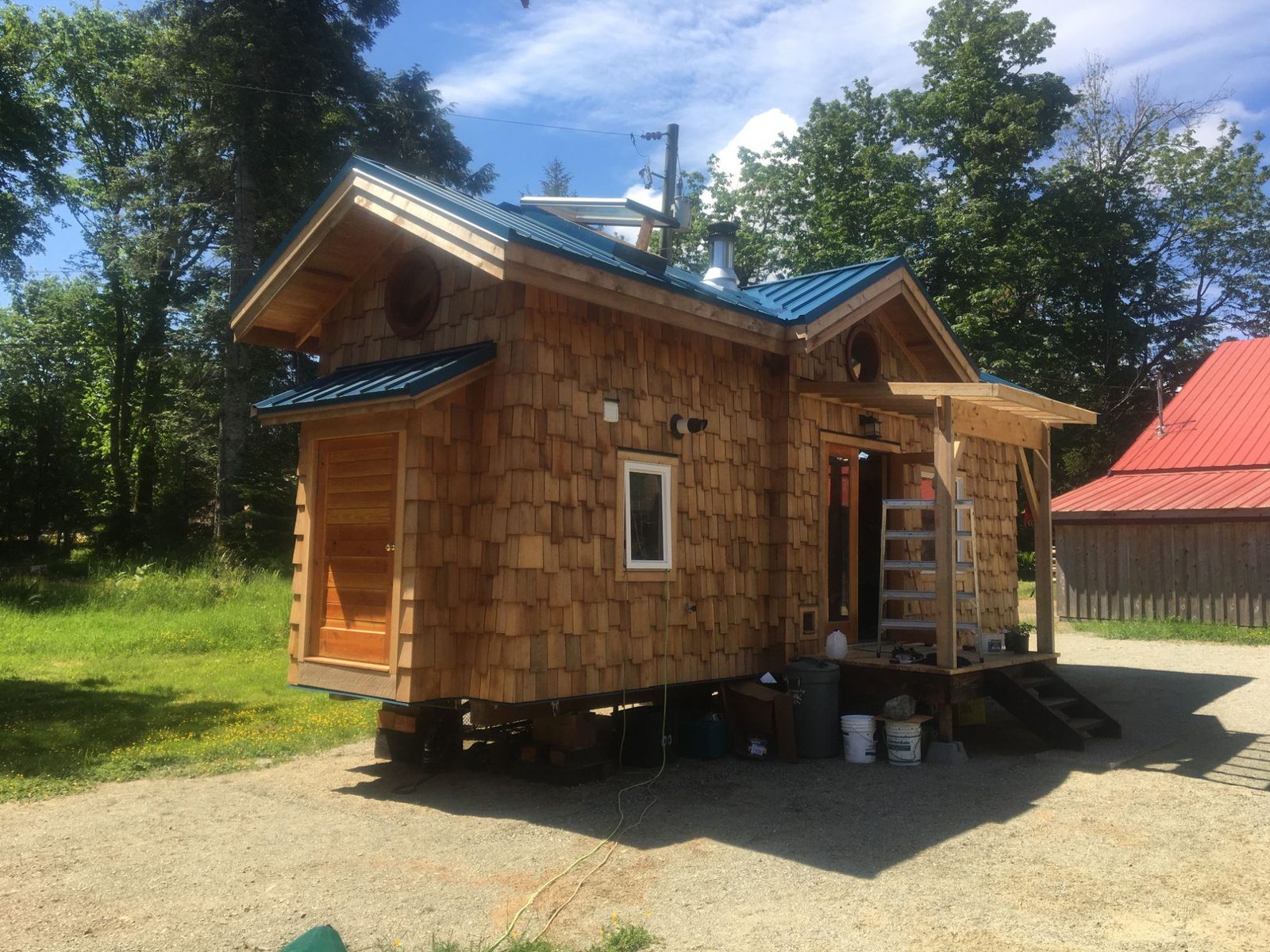 Finished cedar shingle tiny home with metal roof and gabled porch on Quadra Island