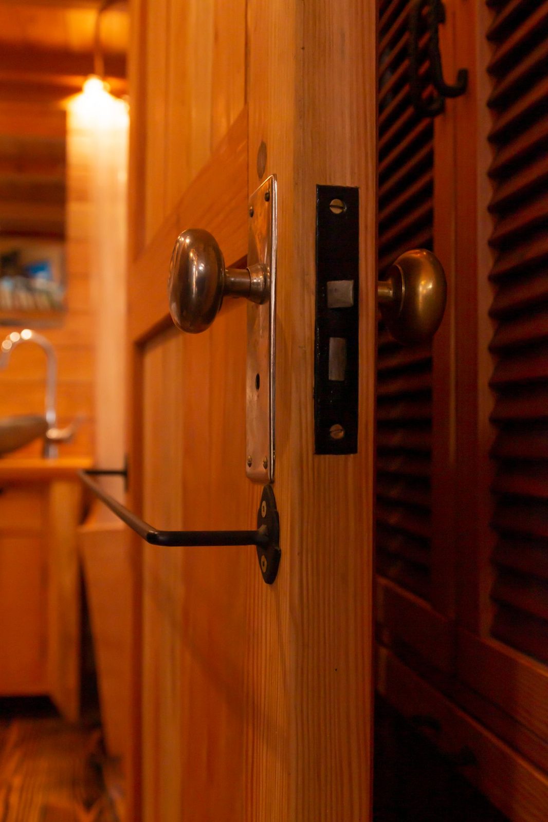 Antique brass door knobs and mortise latch on a wood door inside a tiny home