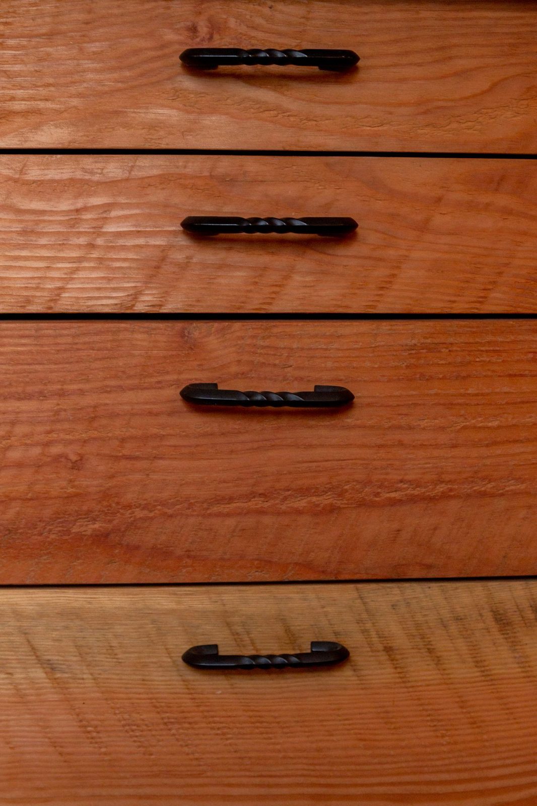 Wood dresser drawers with hand-forged black iron pull handles in a tiny home