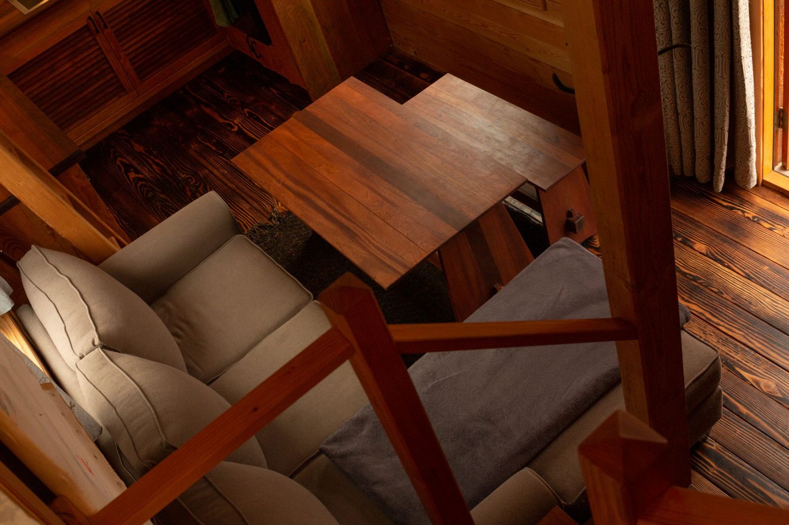 Overhead loft view of a tiny home living area with sofa, table and reclaimed wood floors