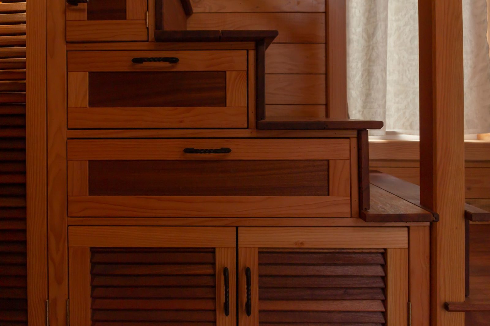 Custom staircase with built-in storage drawers and cabinets in a tiny home interior